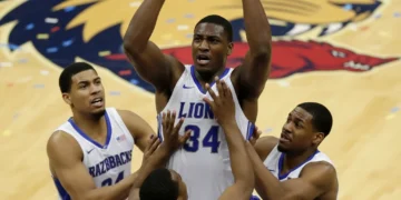 NBA player securing a defensive rebound during a competitive game, surrounded by opponents.