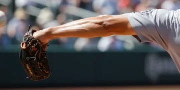 Baseball pitcher's arm in mid-pitch motion, emphasizing muscle strain and injury risk.